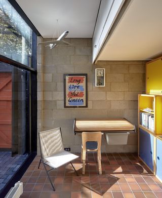 Study with wooden table and blue and yellow cupboards in Jason Mclean's house in Camberwell.