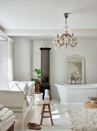 white bathroom with sheepskin rug, wood flooring and white walls with freestanding tub