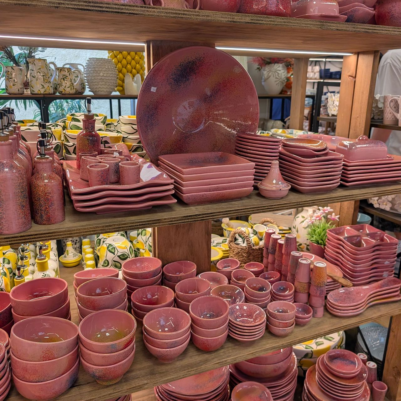 Array of terracotta coloured pottery on wooden shelves