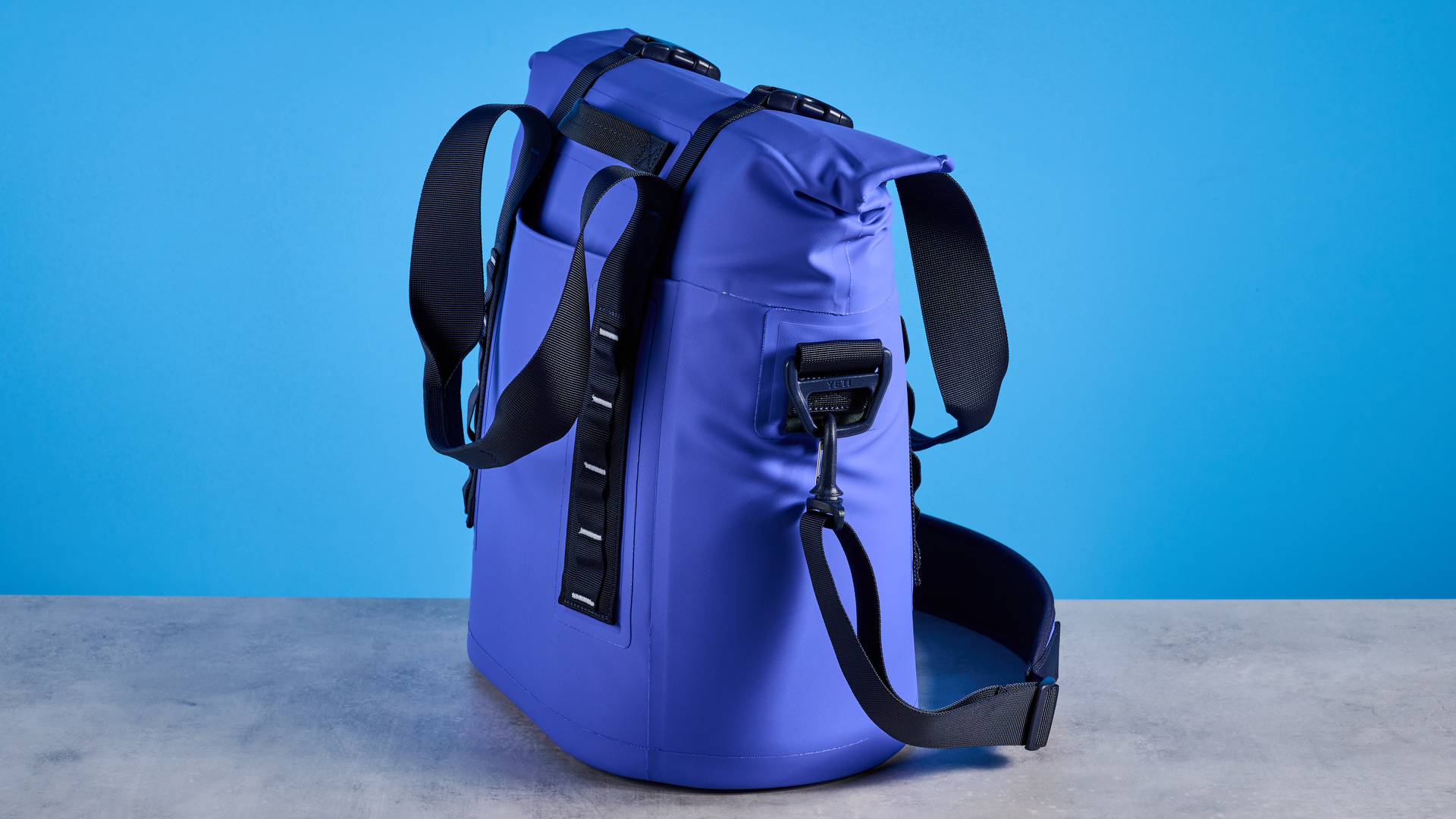 the yeti hopper m15 cool bag with a padded carry strap, handles, and a 15 quart capacity photographed with coke zero cans against a blue background