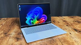 HP OmniBook 5 14 AI PC on a wooden table against a black backdrop.