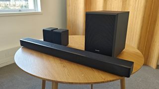 The Hisense AX5125H Dolby Atmos soundbar system, pictured on a round, wooden table