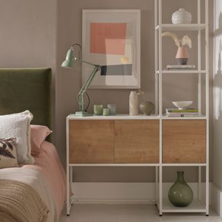 bedroom wall decor ideas, bedroom with taupe walls, shelving unit in alcove, artwork, green velvet bed, pale green desk lamp, pale pink and off white bedding