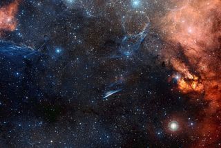This image of the region of sky around the Pencil Nebula shows a spectacular celestial landscape featuring the blue filaments of the Vela supernova remnant, the red glow of clouds of hydrogen and countless stars. Released on Sept. 12, 2012.