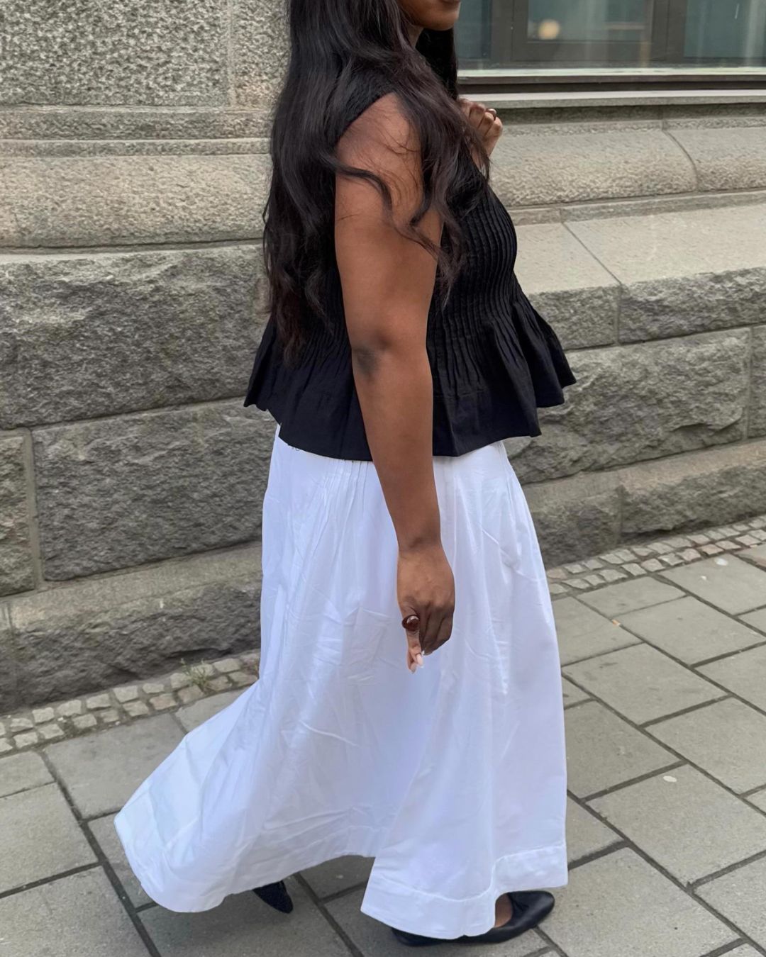 Influencer @nnennaechem wears a white skirt with black ballet flats and a black top.