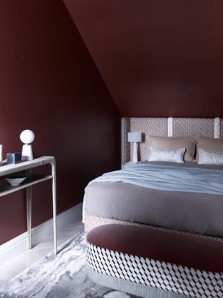 claret coloured bedroom with patterned bedhead and pale accessories