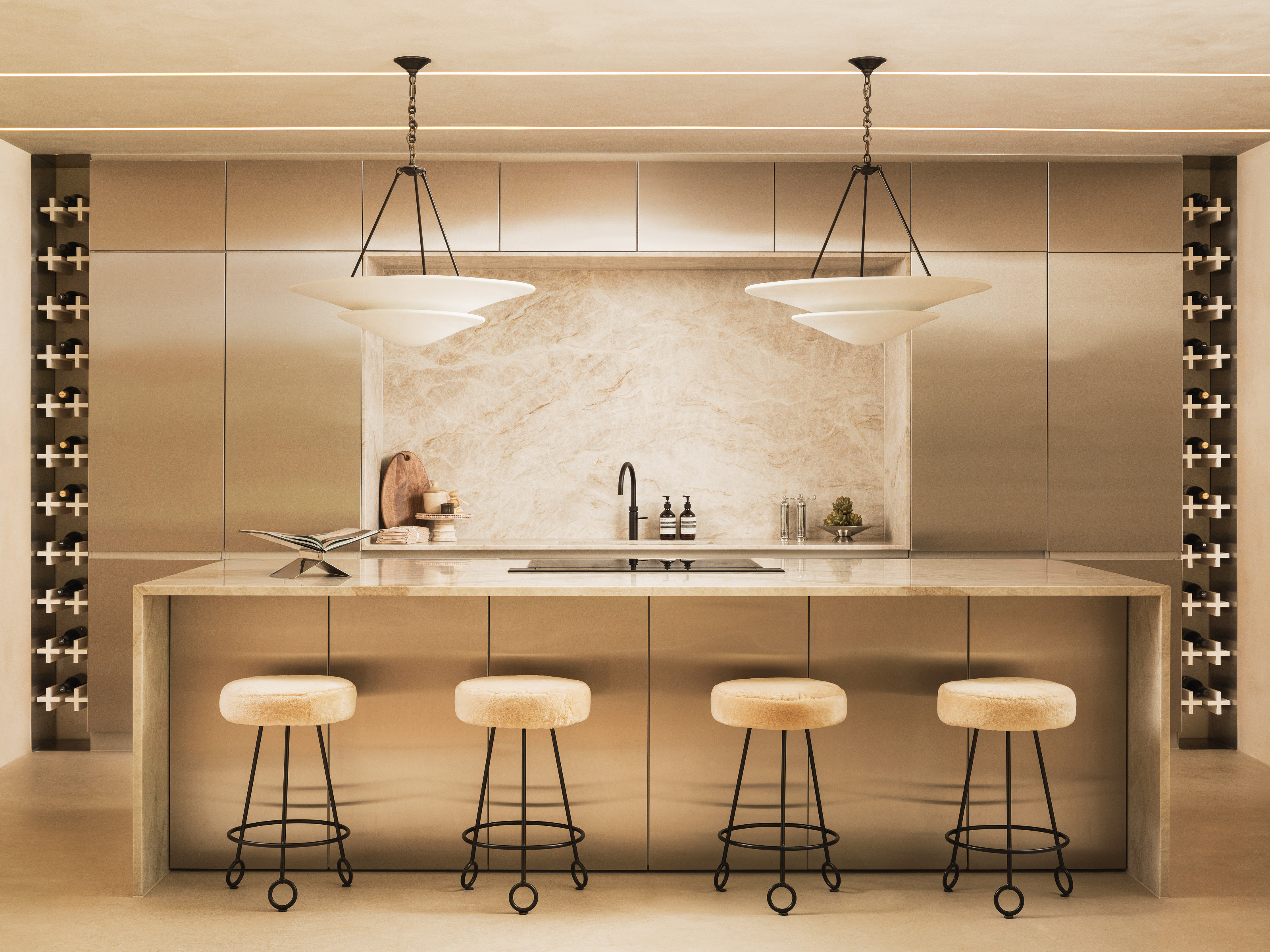 Stainless steel kitchen with cream marble splashback and cream and black metal bar stools