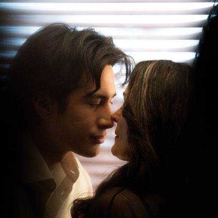 Hudson Williams and Carrie Ann Moss stand closely together in front of window blinds, seen through shadows, in the Crave tv show 'Yaga.'