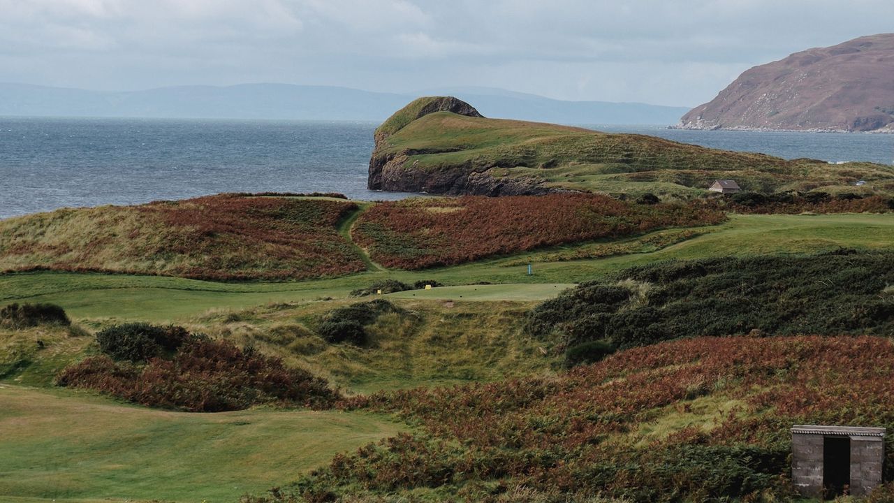A hole at Dunaverty Golf Club with the sea behind it