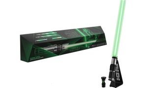 A STAR WARS The Black Series Sabine Wren Force FX Elite Electronic Lightsaber, in its stand with a glowing blade attached, next to its box.