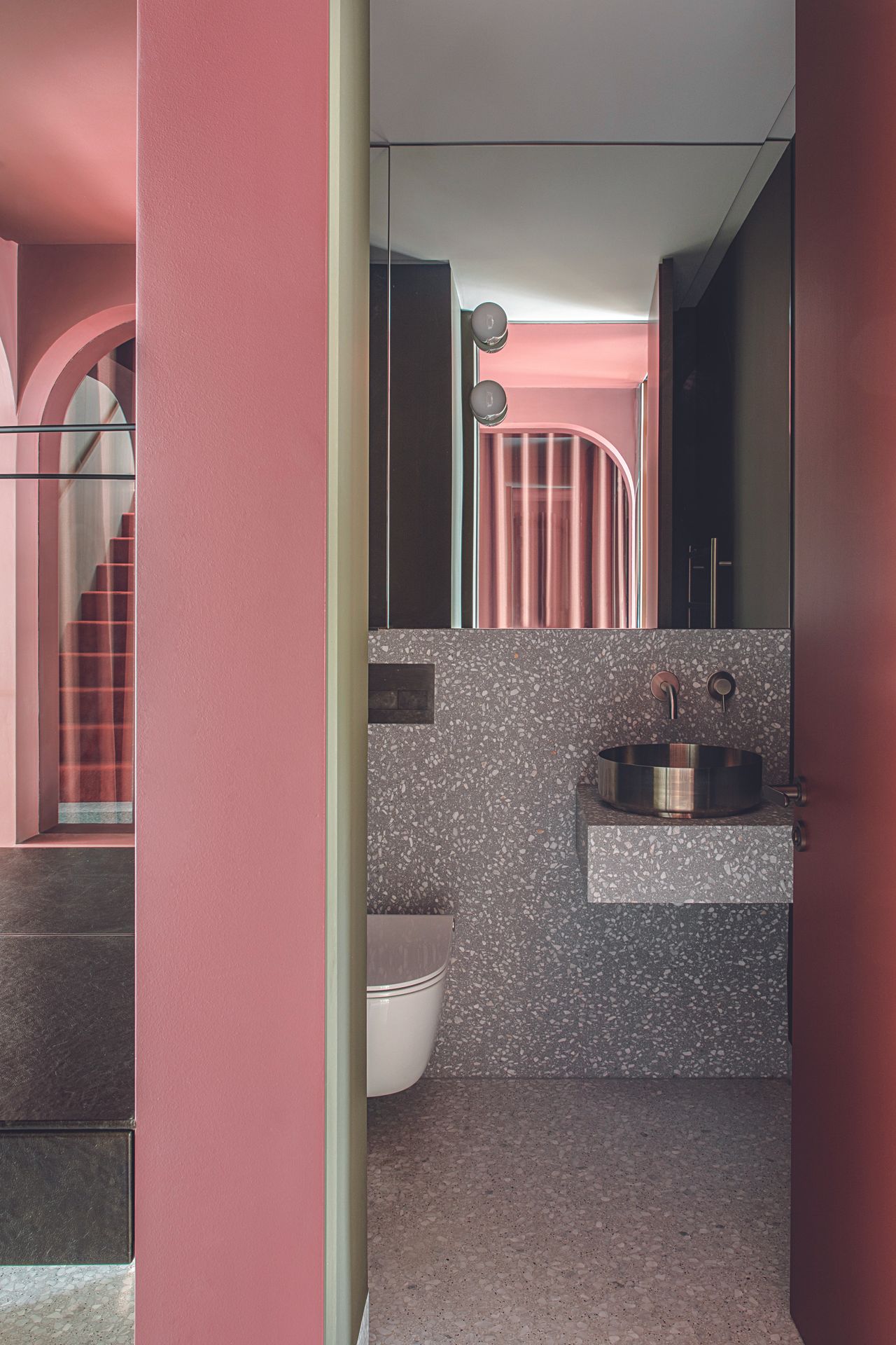 A speckled stone bathroom with pink accents and curved arch details