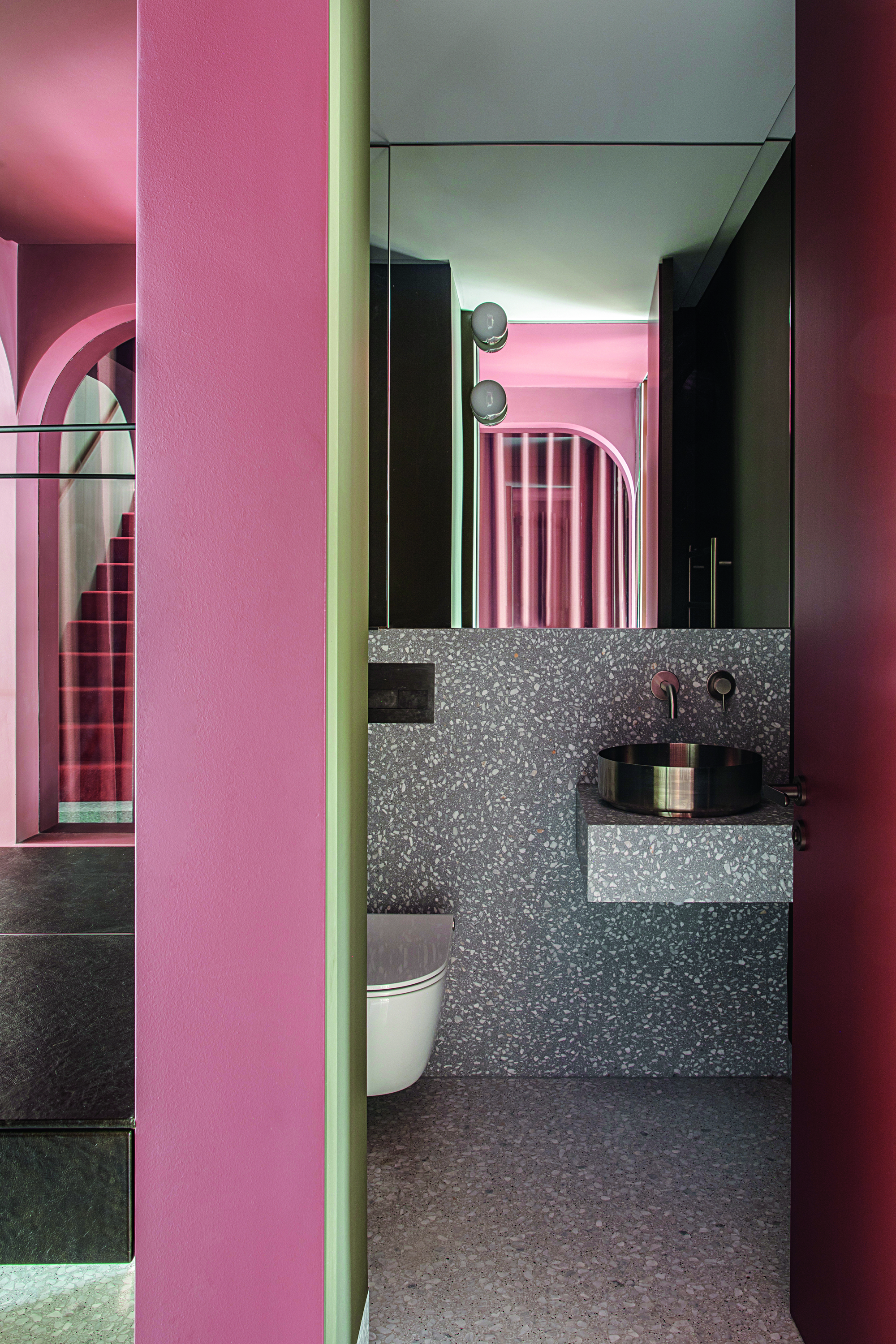 A speckled stone bathroom with pink accents and curved arch details