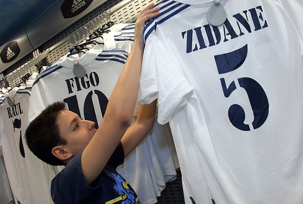 A young fan holds 10 July 2001 a replica of a Real Madrid shirt wearing the name of French international Zinedine Zidane and his new number five, at the club's official shop at the Santiago Bernabeu stadium in Madrid. The passionate fans of Real Madrid are playing a small part in helping ease the financial burden of seeing their beloved team splash out a world record transfer fee for Zinedine Zidane.