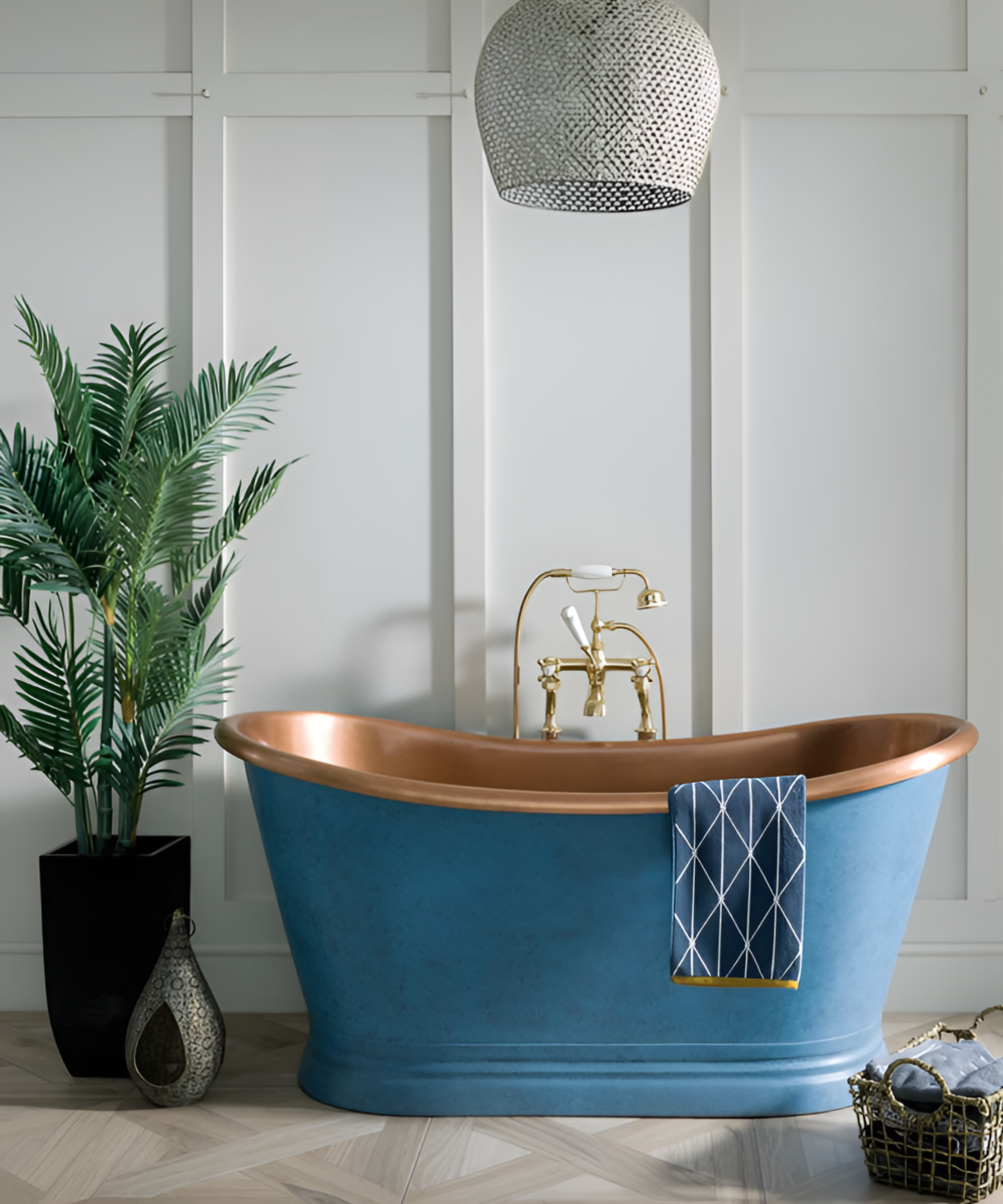 Blue and gold freestanding bath in front of white paneled wall and next to large plant