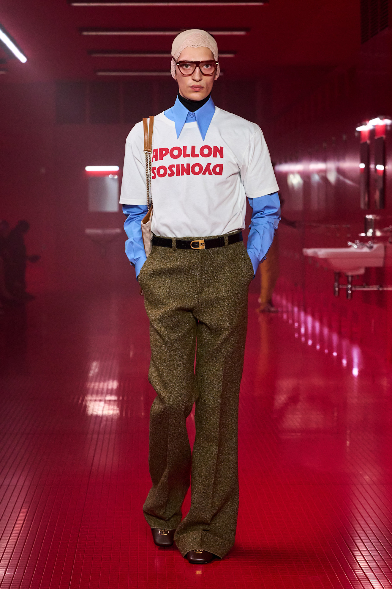 Image of the Valentino autumn/winter 2025 show. The model wears a blue shirt with a graphic t-shirt layered on top. This image was taken from Launchmetrics.