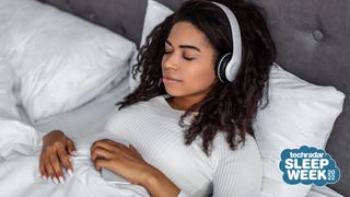 Woman resting in bed holding phone and wearing headphones