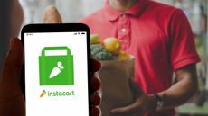 Instacart logo on smartphone with grocery delivery person blurred in background