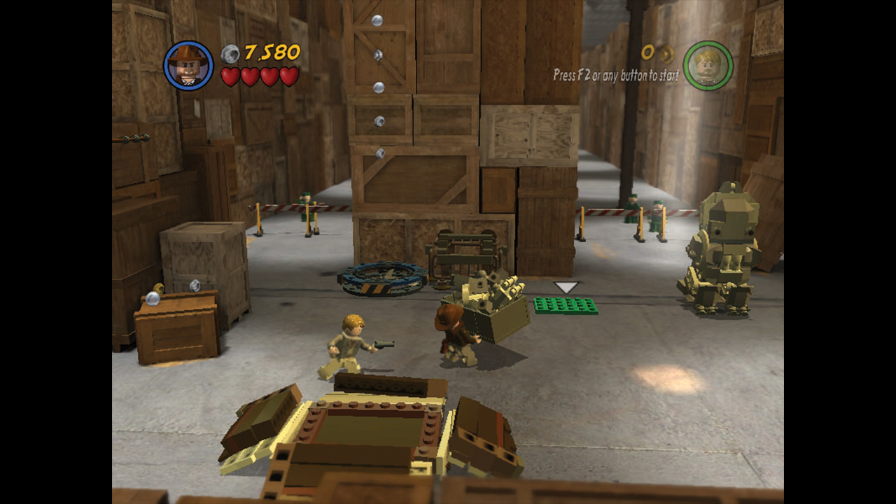Indy carries a large crate of lego bricks in Lego Indiana Jones 2: The Adventure Continues for PC - from Retro Gamer magazine
