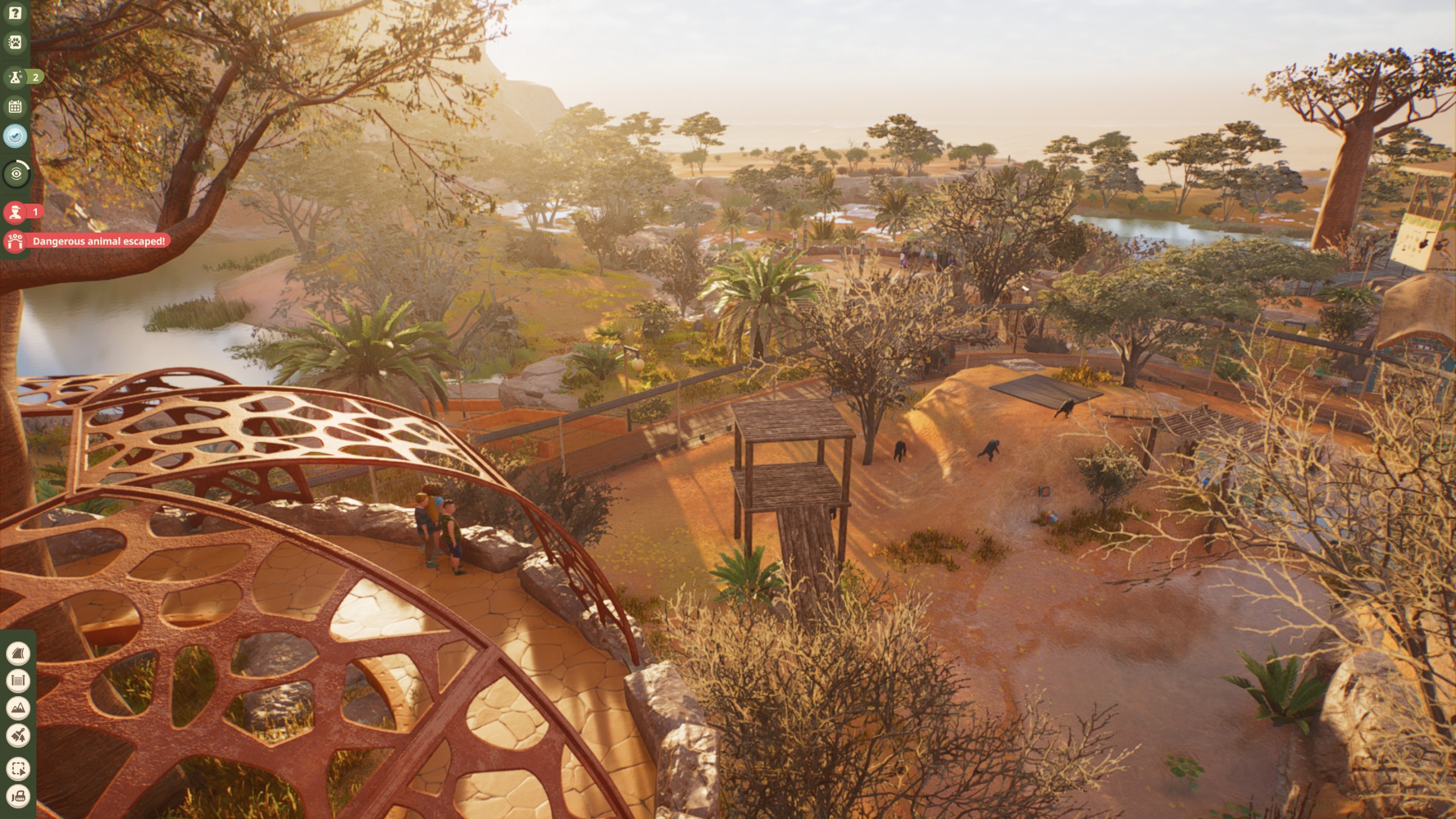 Visitors in a zoo watching gorillas at sunset from a circular viewing platform in Planet Zoo 2.