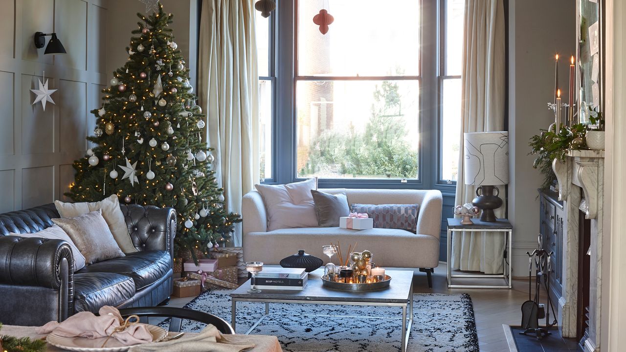 Grey living room with bay windows and white sofa, decorated for Christmas with a large Christmas tree