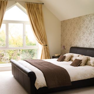 bedroom with wallpaper on wall and lather bed