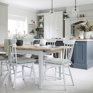 an open plan kitchen diner with shaker-style cabinets and a farmhouse-style dining white table and chairs