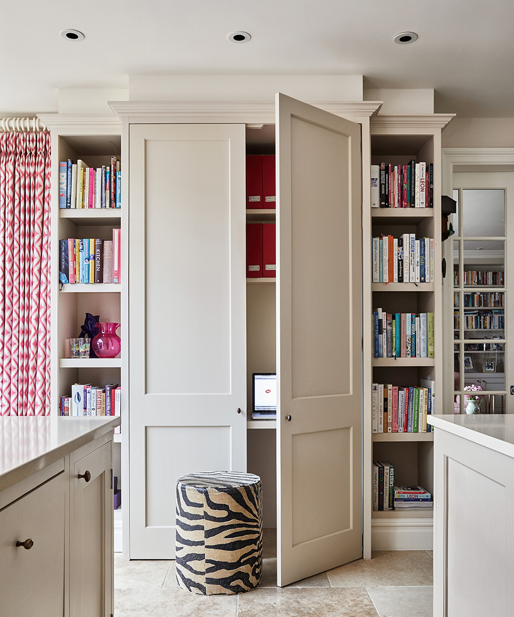 A zebra print stool in front of floor to ceiling cabinets surrounded by bookshelves with LED downlights