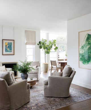 living room with white walls and four armchairs a rug and bright artworks