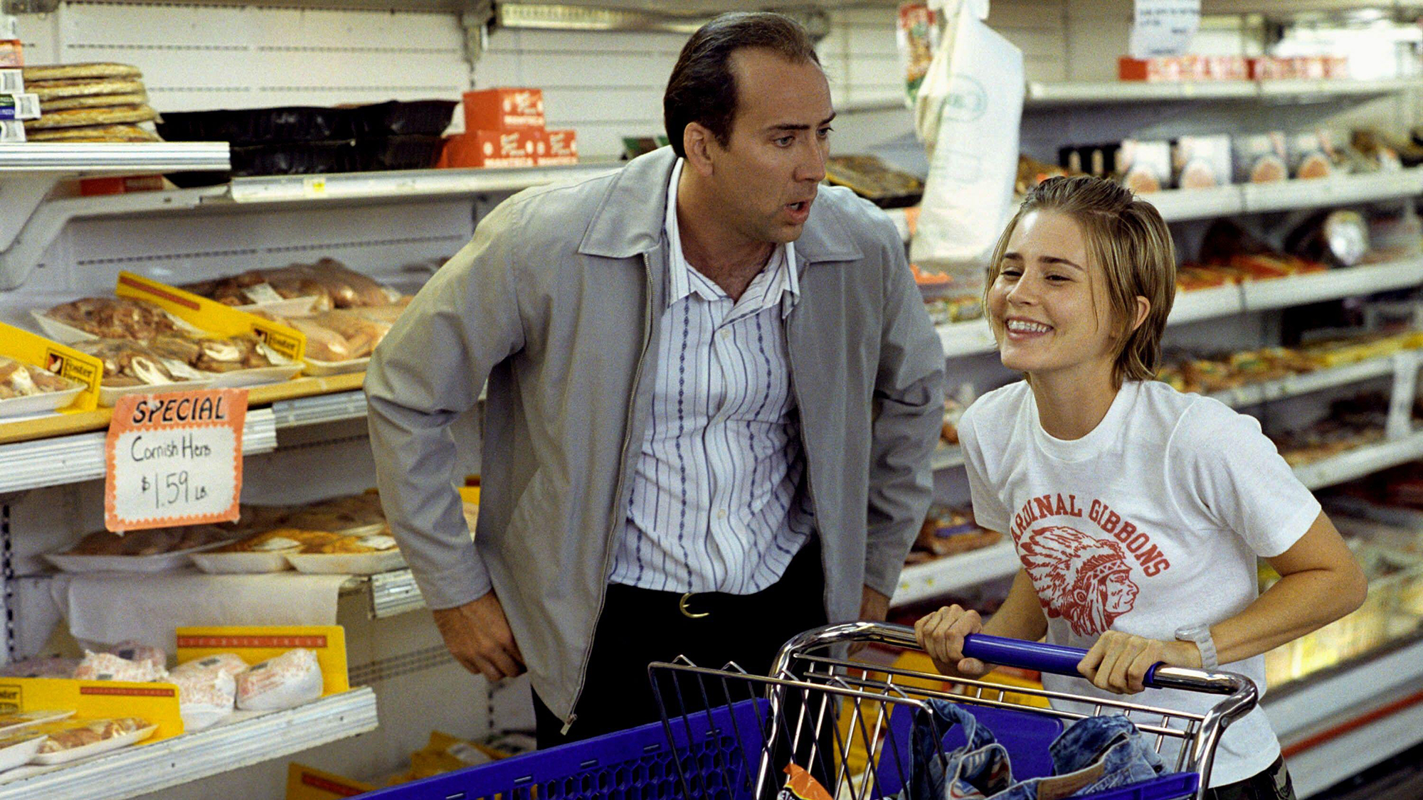 (De izquierda a derecha) Nicholas Cage como Roy luciendo sorprendido mientras y Alison Lohman como Angela se ríe mientras compra en Matchstick Men