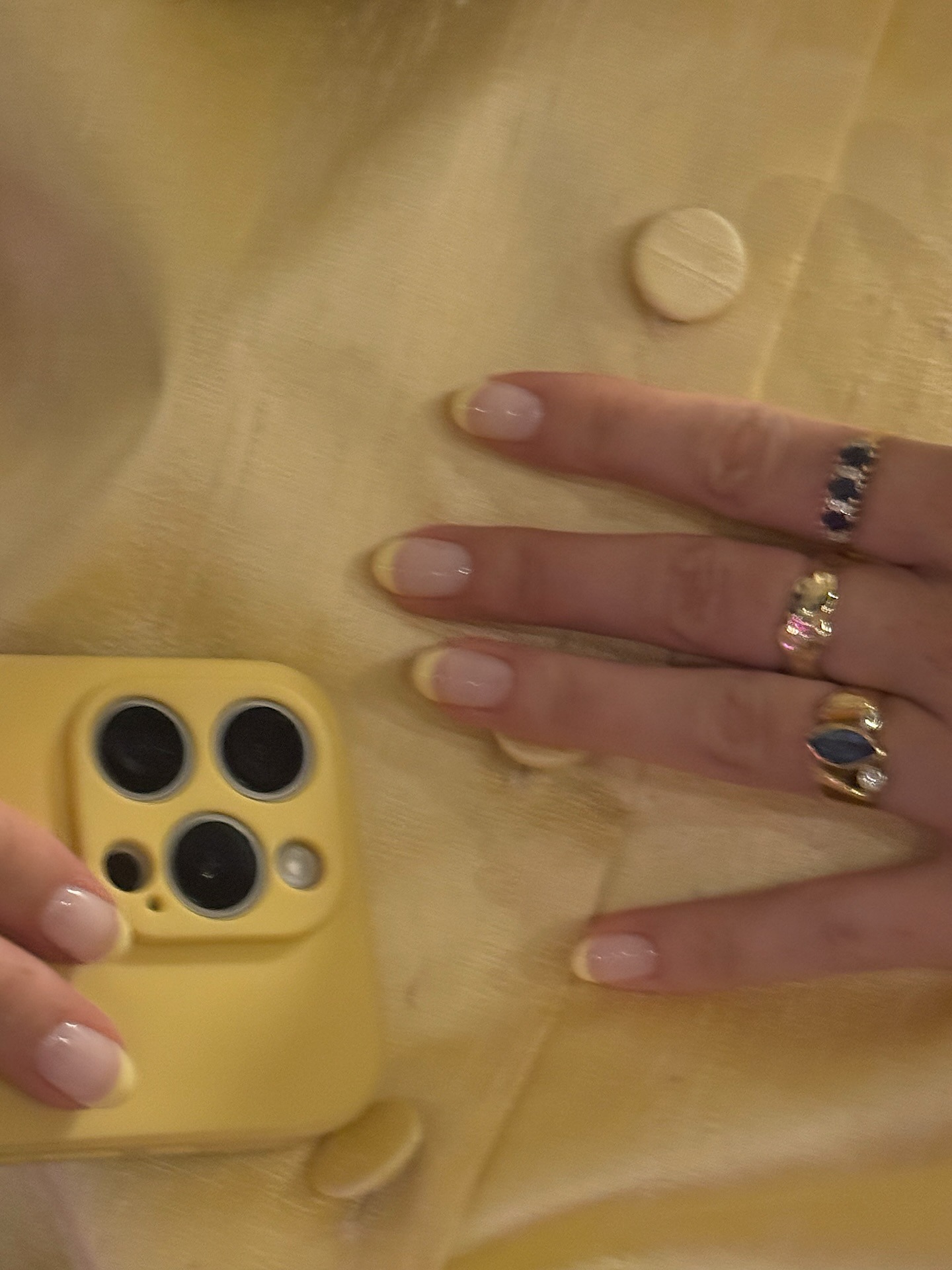 A woman wearing a butter yellow shirt with a matching French tip manicure