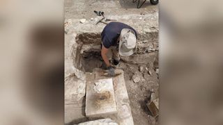 A researcher unearths a foundation stone in an archaeological site.