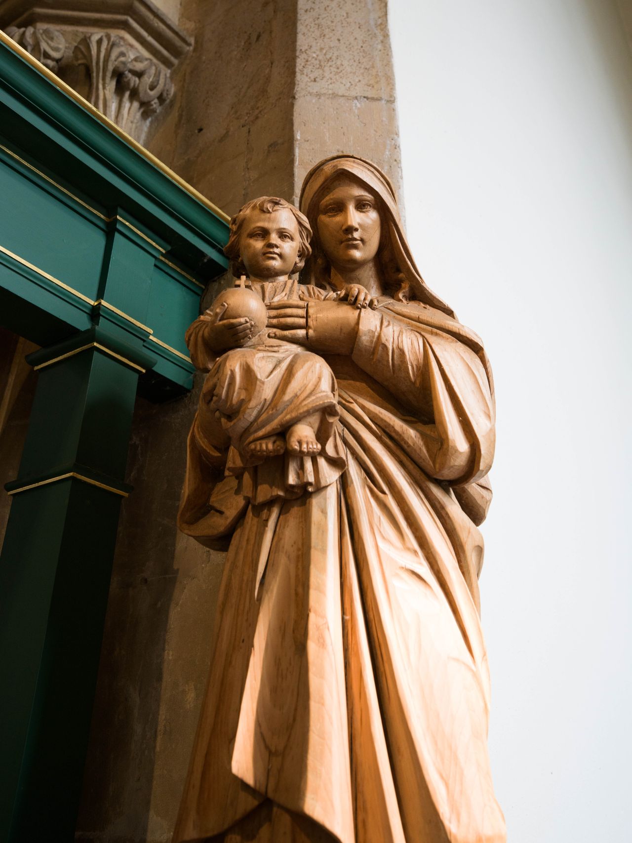 A photo of a Christian religious statue, showing a woman holding a child, taken in a Cathedral.