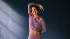 Woman setting up for wall angels exercise against a wall, smiling