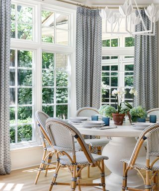 beautiful sun room dining room with round pedestal table and navy drapes