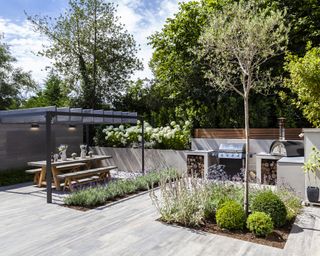 modern paved garden with pergola, outdoor kitchen, pizza oven and built in BBQ