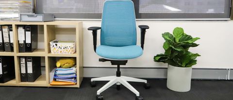 Steelcase Personality Plus office chair in blue standing by a wall