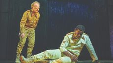Toby Jones as Iago stands over David Harewood as Othello