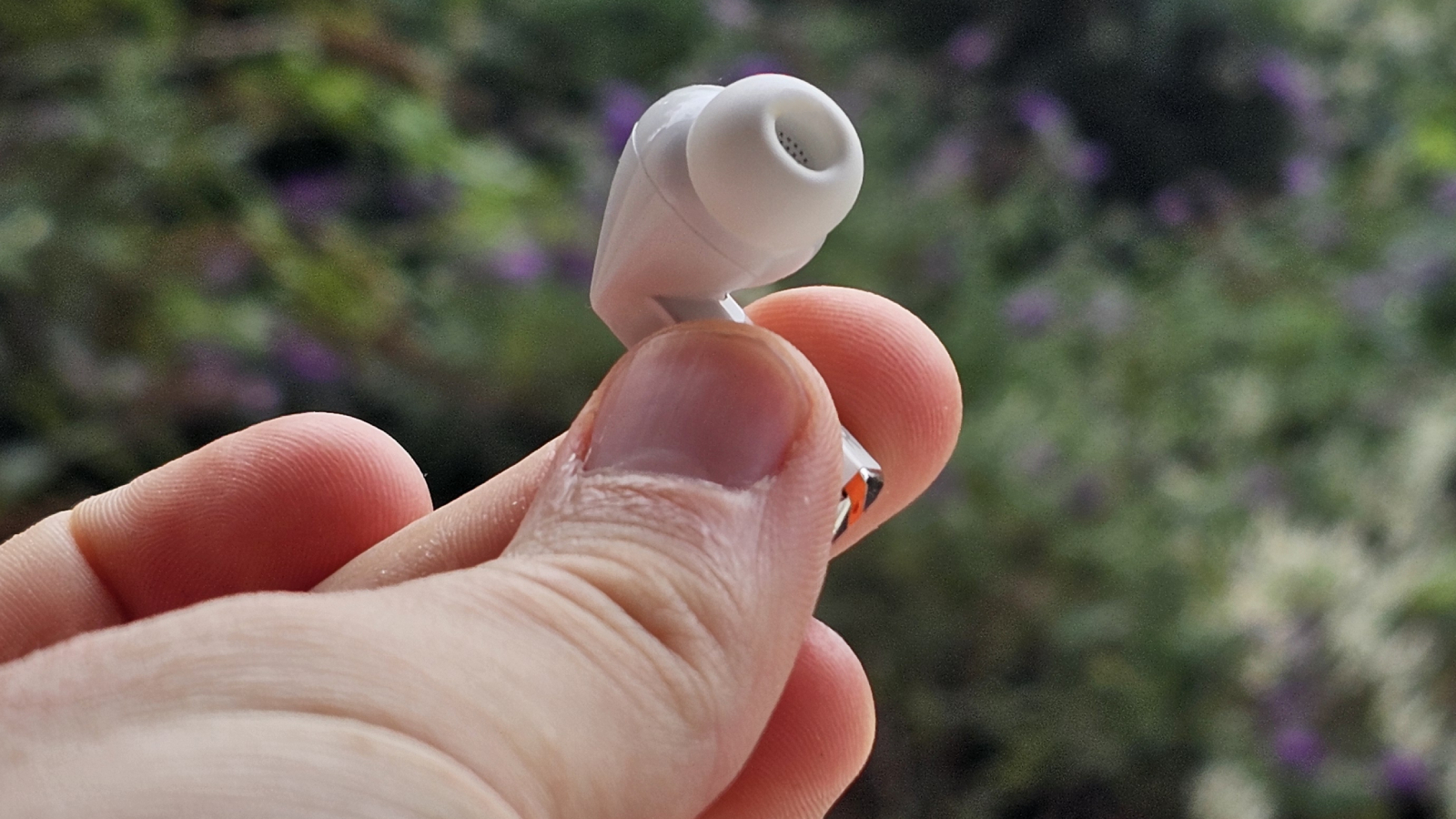 The Samsung Galaxy Buds 3 Pro against a leafy background.