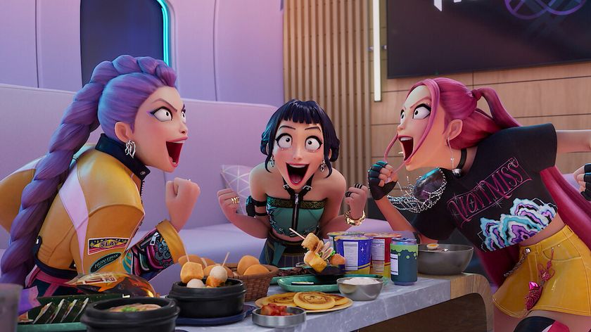 Rumi, Zoey, and Mira cheer as they sit at a table full of food in Kpop Demon Hunters