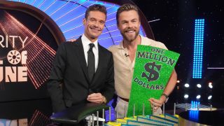RYAN SEACREST and DEREK HOUGH side by side smiling on the set of Wheel of Fortune.