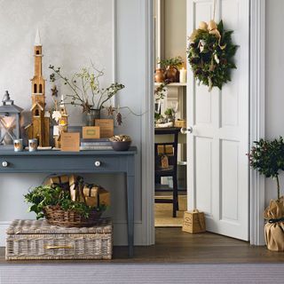 rustic festive hallway with wreath, small tree and wooden decorations and baskets