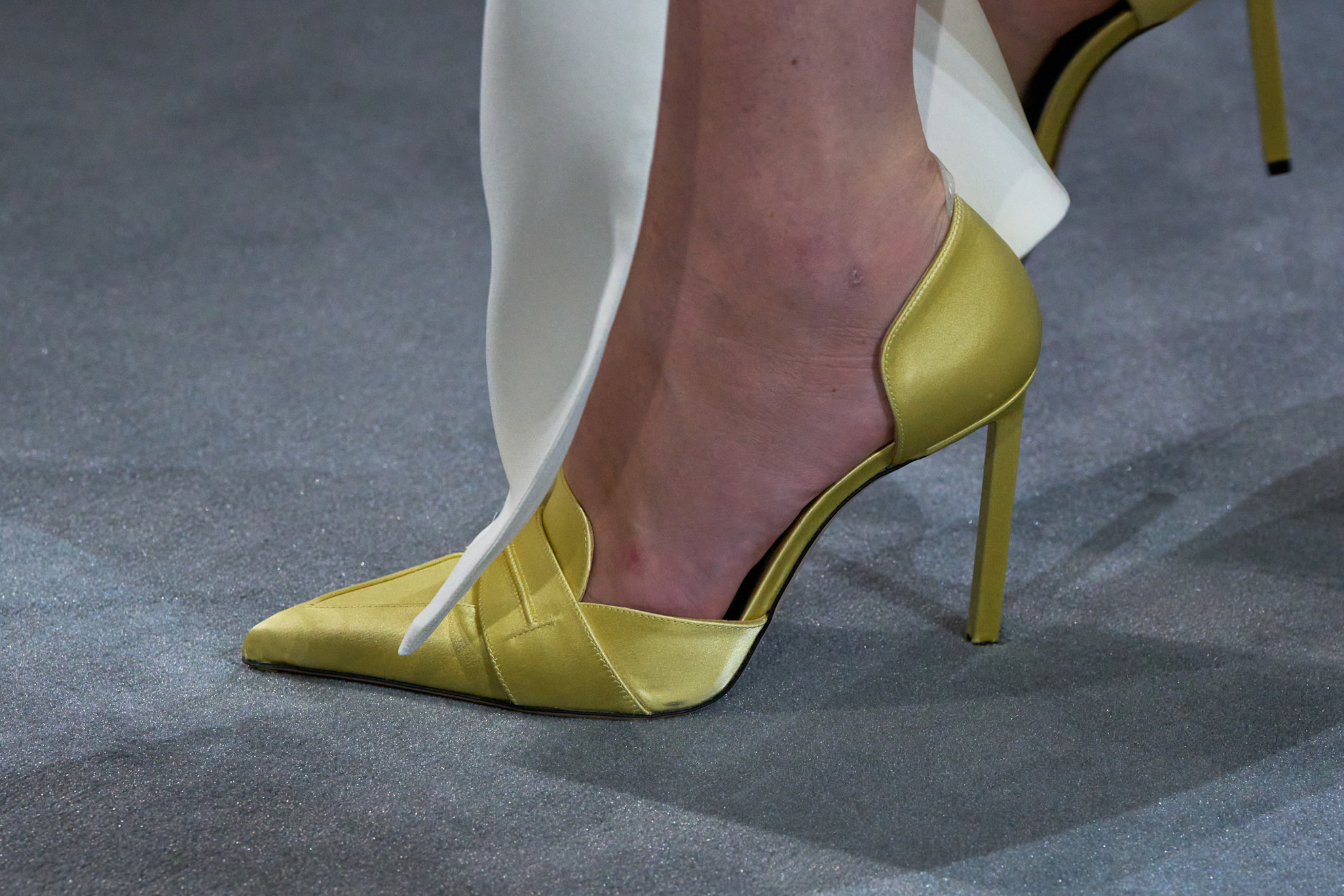 An image of the Tom Ford autumn/winter runway show. The model wears a satin Chartreuse heel winter shoe colour trend of 2025.