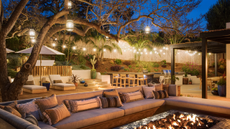 An outdoor space lit with a firepit, rattan lantens and string lights