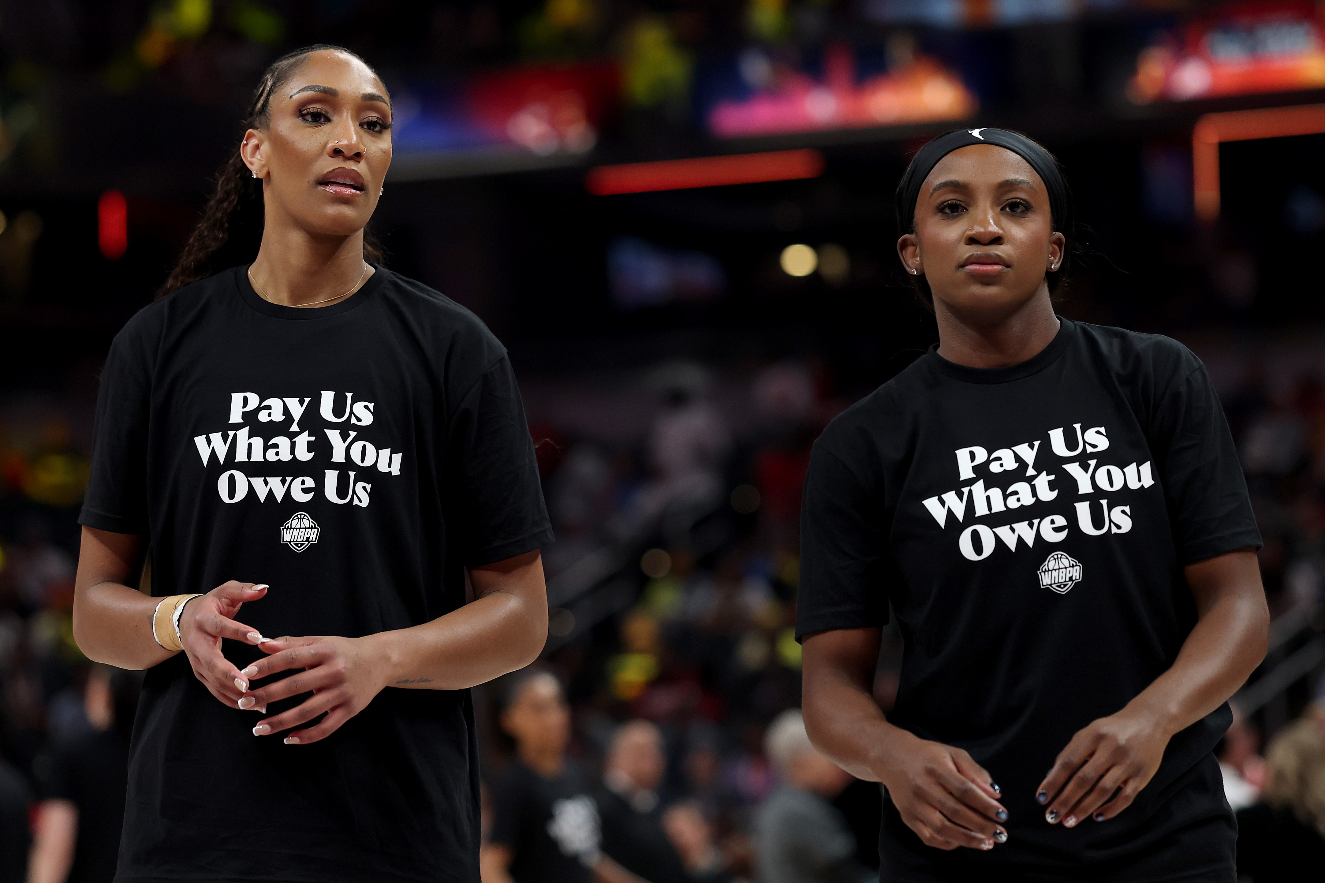 Aja Wilson and another WNBA player wearing pay us what you owe us shirts at the all star game