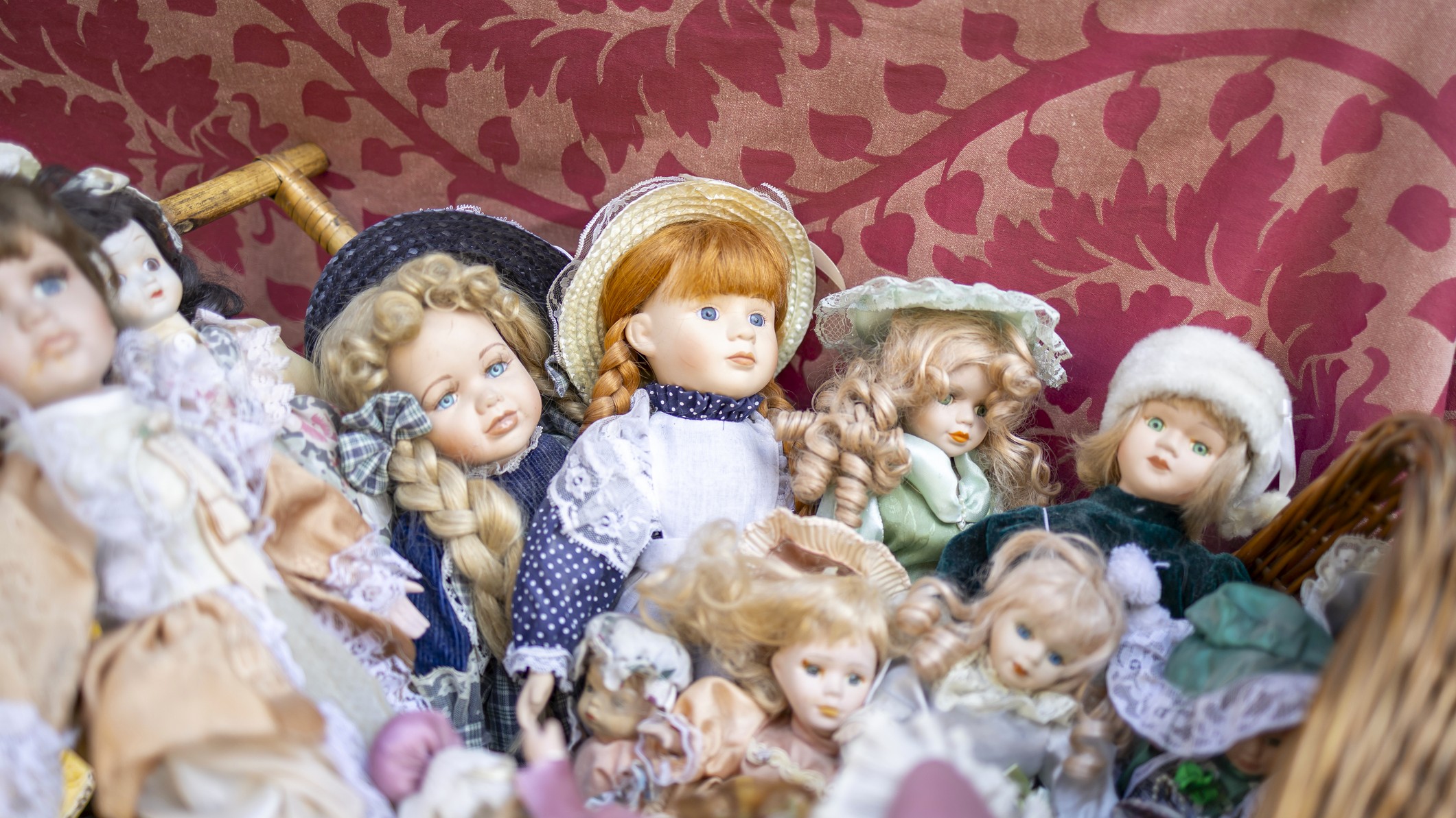 Antique dolls are piled up in a chair.