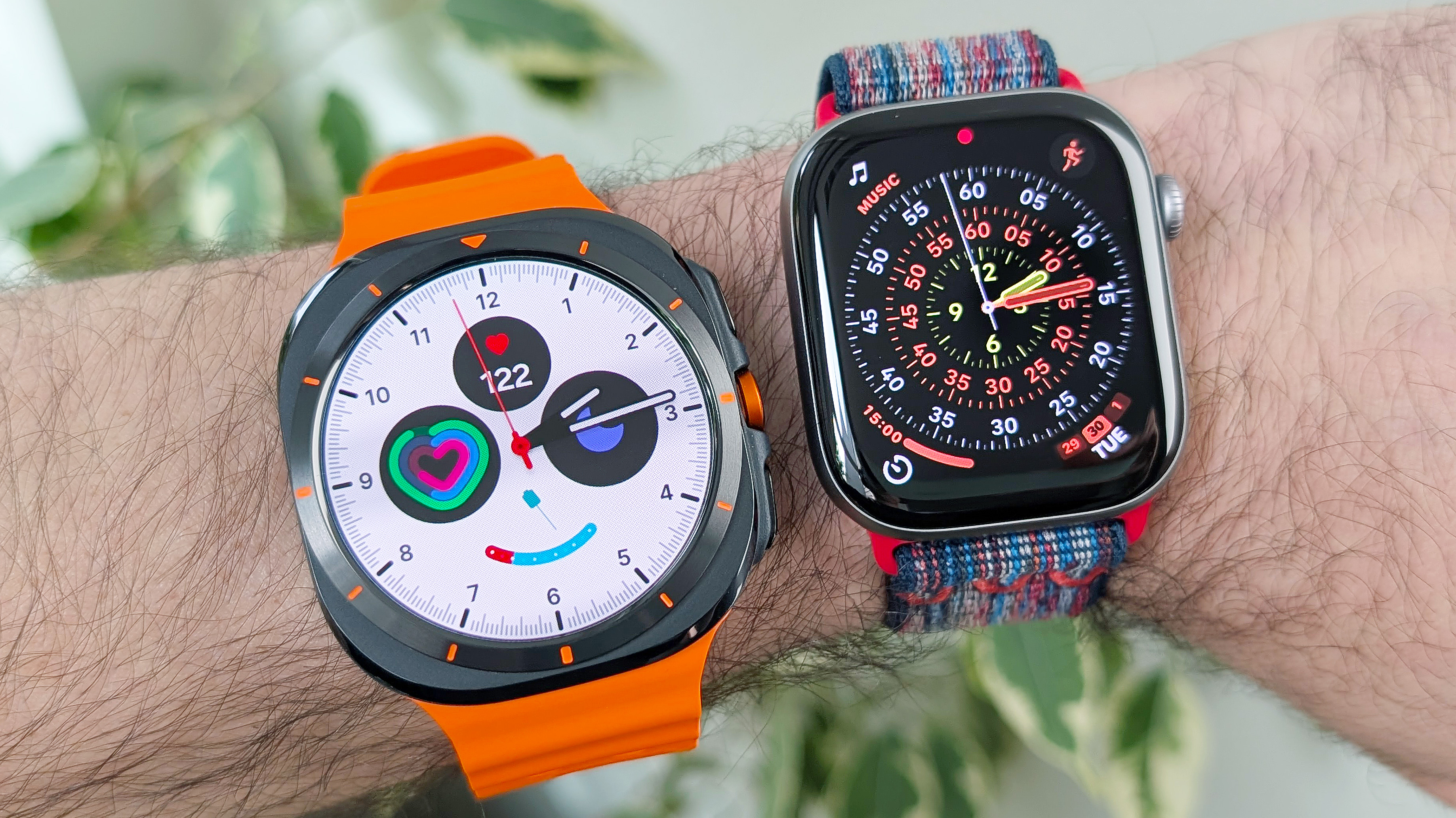 Close-up of the Samsung Galaxy Watch Ultra and Apple Watch Series 11 on a user&#039;s wrist