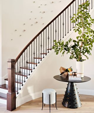 A curved entryway staircase and a small table with a tall plant