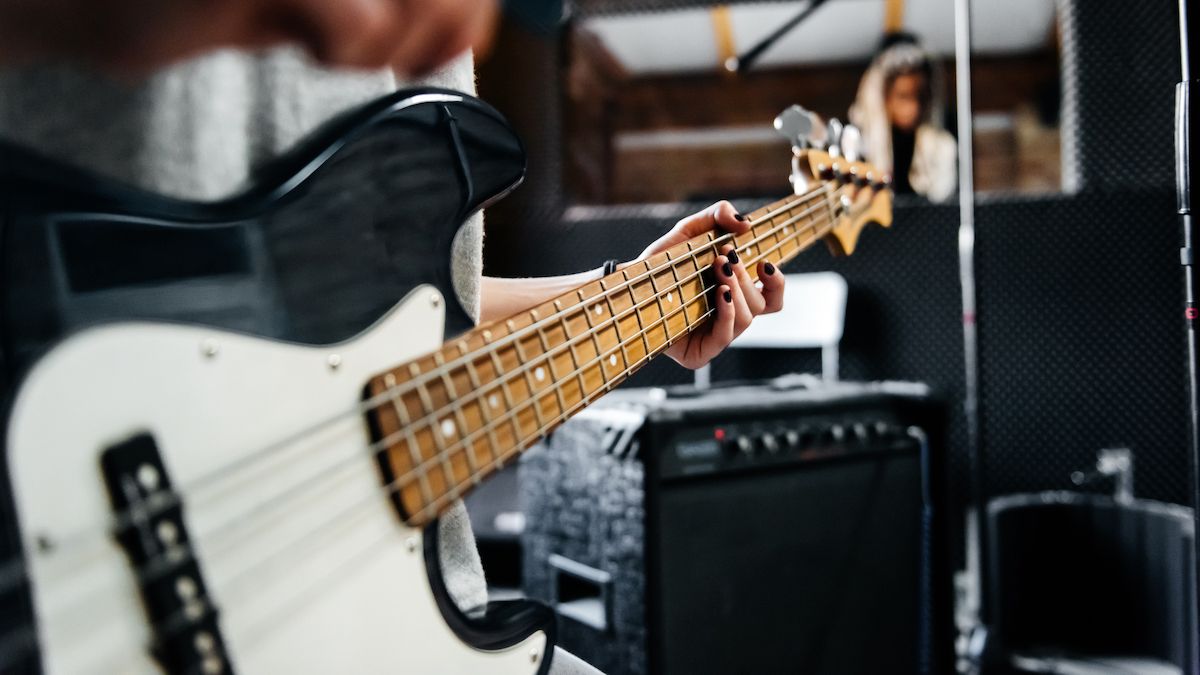 Close-up for woman playing a black and white bass guitar