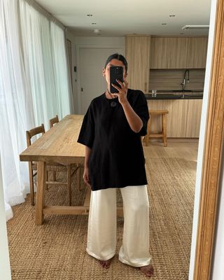 @monikh taking a mirror selfie wearing baggy black tshirt and satin pants