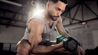 Man performs concentration curl with dumbbell